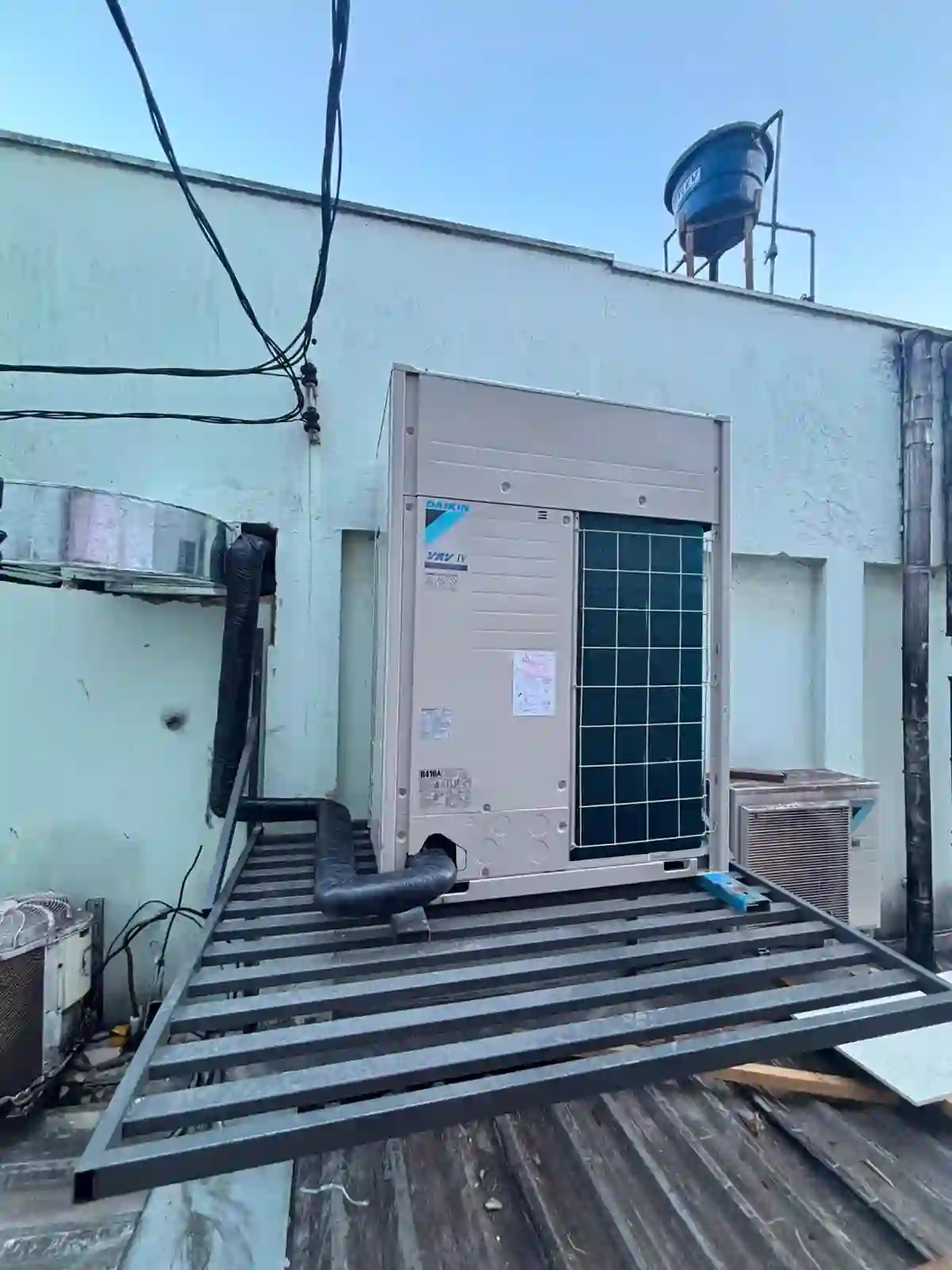 Unidade Daikin VRV IV de grande porte instalada em laje sobre estrutura metálica nova, com céu azul.